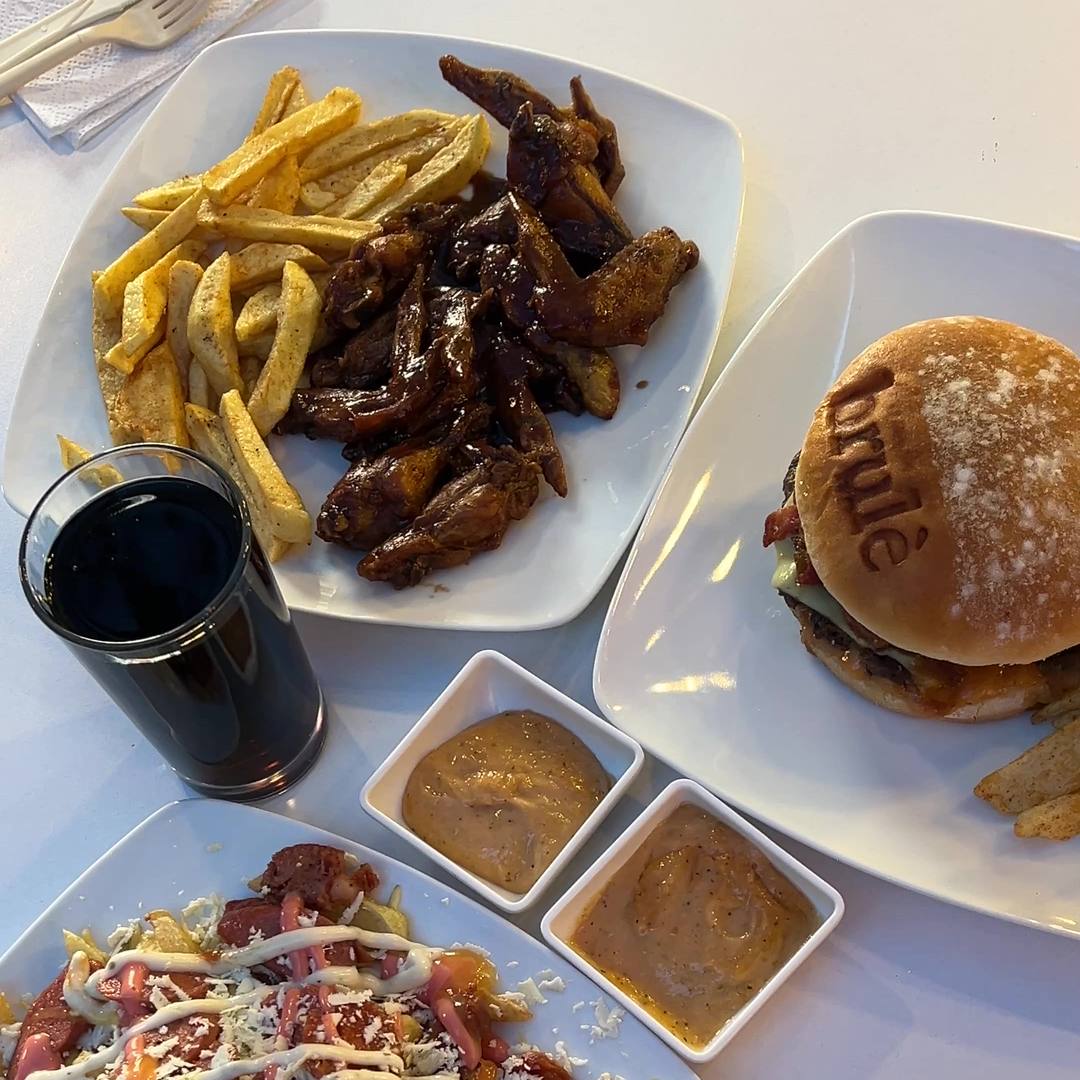 Mesa servida en Brulè: alitas con papa francesa, hamburguesa artesanal, papas Barranquilla y salsas de la casa